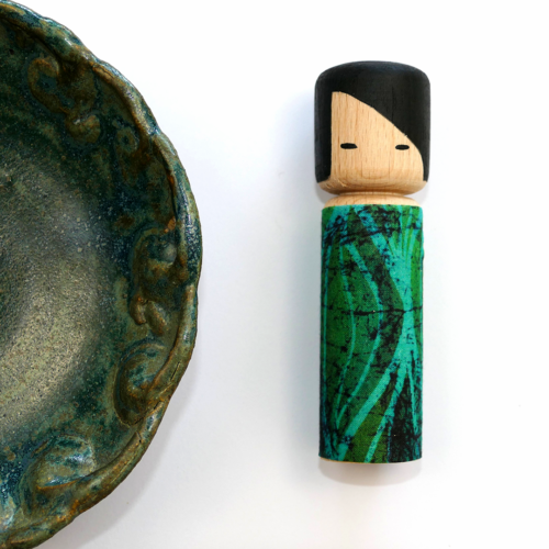 Drewniana laleczka Batikoshi kokeshi w kolorze zielonym - na imię ma Yujo. Laleczka ubrana jest w prinart zielonego batiku - materiału wykonanego w jawajskiej technice malowania tkaniny. Laleczka Batikoshi jest talizmanem, figurką z intencją - Yujo wspiera przyjaźń. Symbolizuje spotkanie pokrewnych dusz.